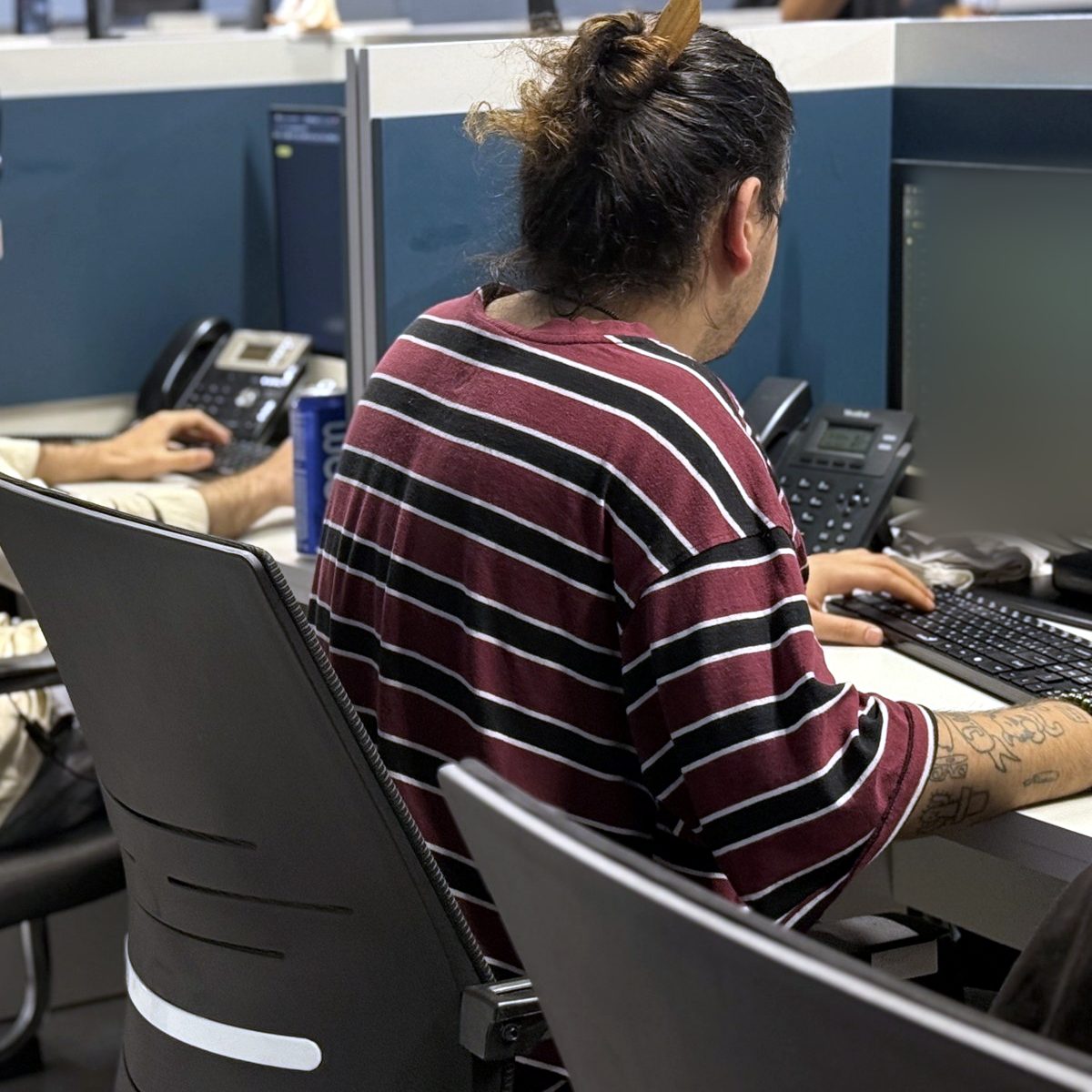 DSPro agent in a striped shirt working a call at her desk