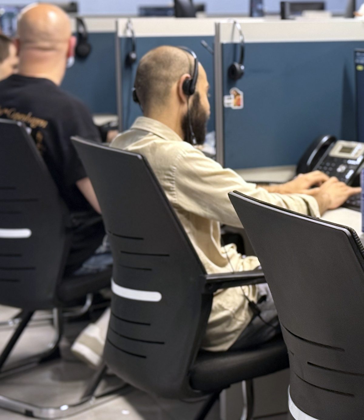 DSPro agents in headsets at their desks, seen from behind